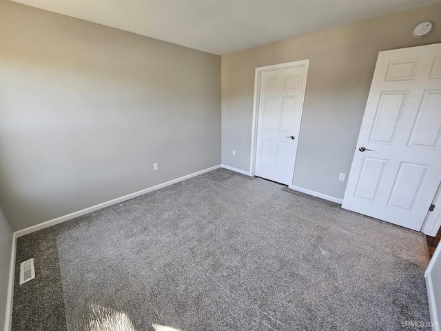 unfurnished bedroom featuring baseboards, carpet, and visible vents