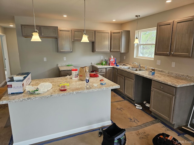 kitchen featuring light stone countertops, decorative light fixtures, a center island, and sink