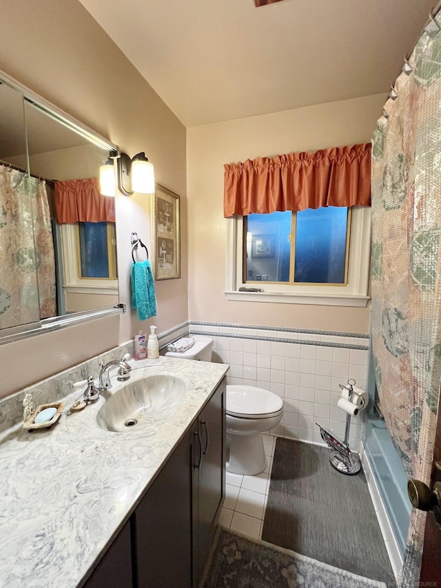 full bathroom with shower / tub combo with curtain, vanity, tile patterned floors, tile walls, and toilet