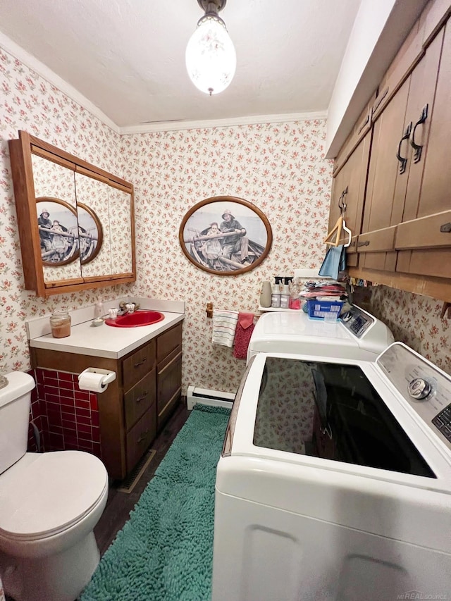 clothes washing area featuring washing machine and clothes dryer, baseboard heating, a sink, laundry area, and wallpapered walls