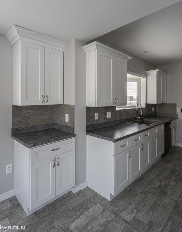 kitchen with white cabinets, backsplash, dishwashing machine, and sink