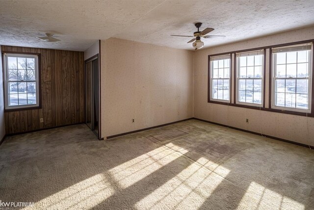 carpeted spare room featuring plenty of natural light, a textured ceiling, and ceiling fan