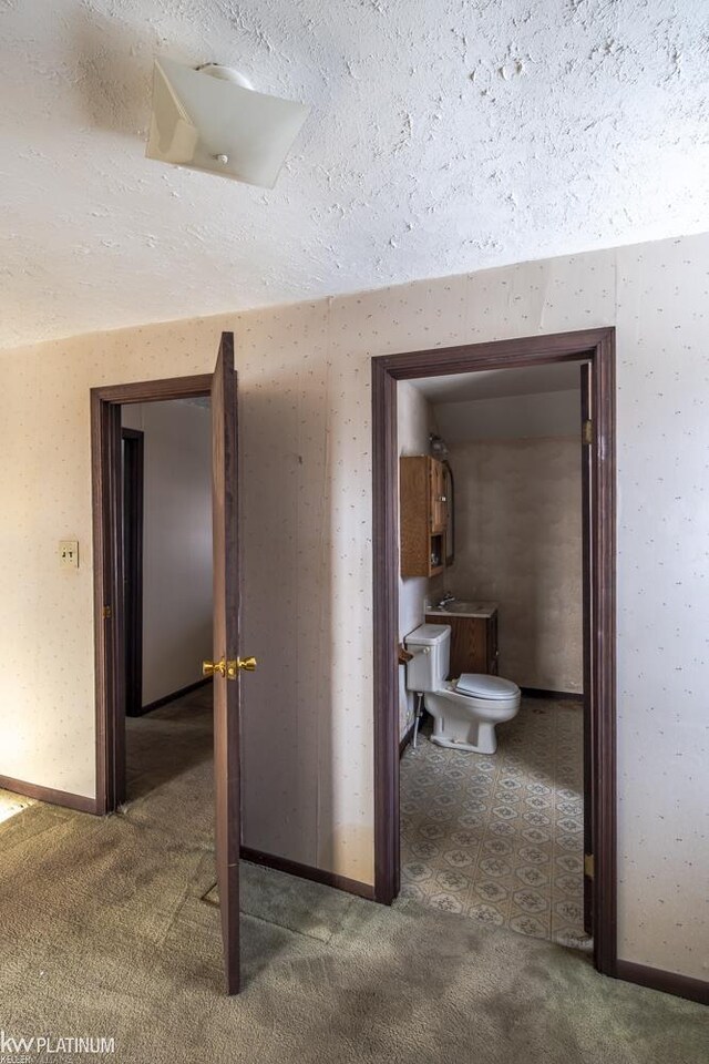 hallway featuring sink, carpet, and a textured ceiling