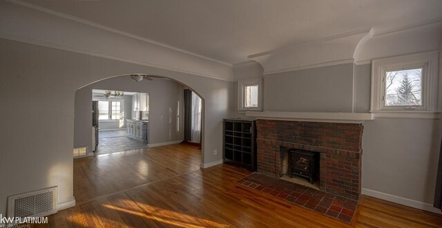 unfurnished living room with plenty of natural light, ceiling fan, a fireplace, and hardwood / wood-style flooring