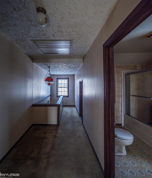 hallway with wood walls, carpet floors, and a textured ceiling