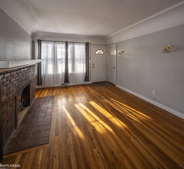 unfurnished living room featuring crown molding, hardwood / wood-style flooring, and a brick fireplace