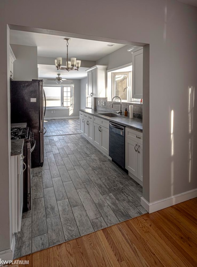 kitchen featuring black dishwasher, stainless steel gas range oven, hardwood / wood-style flooring, and white cabinets