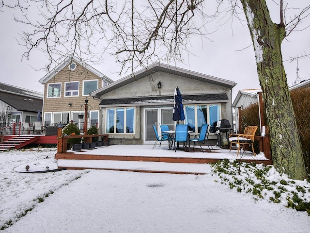 snow covered back of property featuring a wooden deck