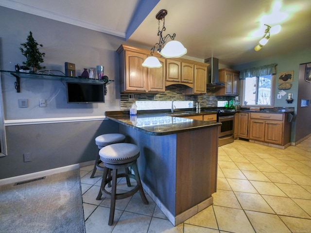 kitchen featuring wall chimney range hood, light tile patterned floors, decorative light fixtures, stainless steel range oven, and kitchen peninsula