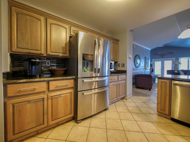 kitchen with backsplash, light tile patterned flooring, stainless steel appliances, and dark stone counters