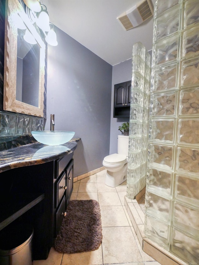 bathroom with toilet, vanity, and tile patterned floors