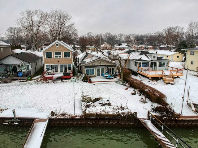 snow covered rear of property featuring a deck with water view