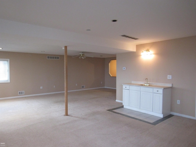 basement featuring light carpet, ceiling fan, and indoor wet bar