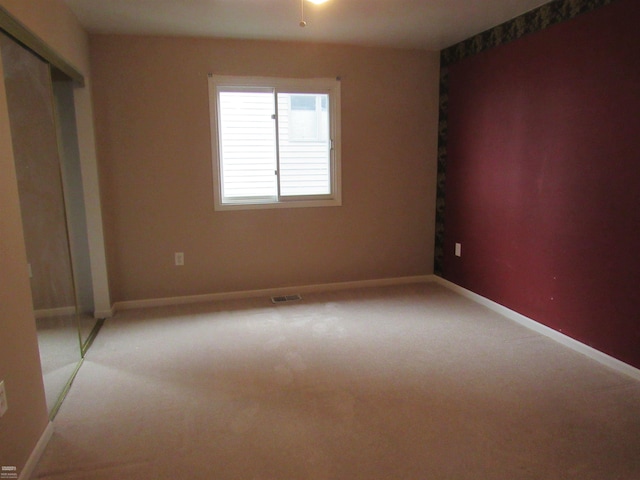 unfurnished bedroom with a closet and light carpet