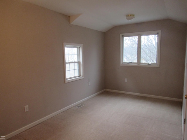 carpeted empty room with lofted ceiling