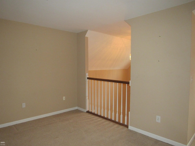 spare room featuring carpet and lofted ceiling