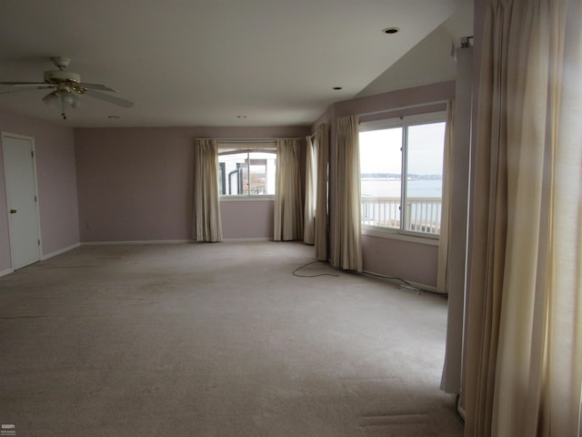 carpeted spare room featuring ceiling fan and a water view