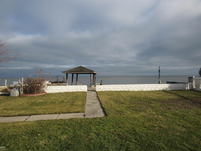 view of dock featuring a gazebo, a water view, and a lawn