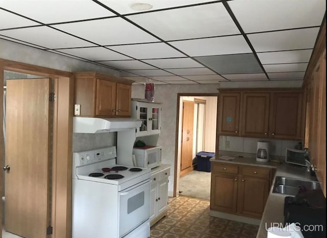 kitchen featuring white appliances, a drop ceiling, sink, and light tile floors