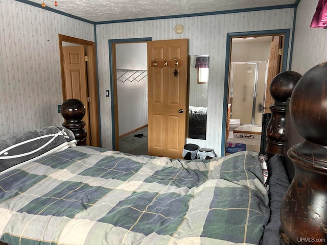 bedroom featuring a spacious closet, ensuite bathroom, carpet flooring, a textured ceiling, and a closet