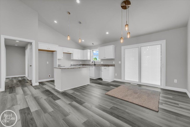 kitchen with hardwood / wood-style floors, a center island, decorative light fixtures, and white cabinetry