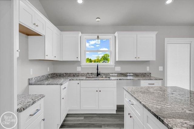 kitchen with white cabinets, dark hardwood / wood-style floors, light stone countertops, and sink