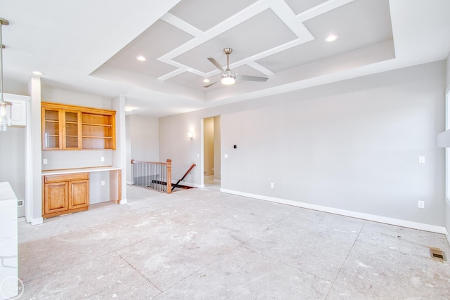 unfurnished living room featuring ceiling fan and a tray ceiling