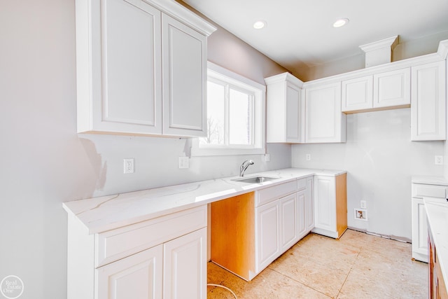 kitchen with sink, light stone counters, white cabinets, and light tile floors