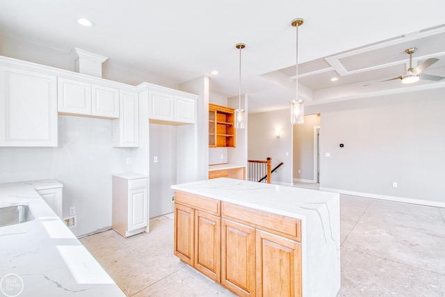 kitchen featuring light stone countertops, ceiling fan, pendant lighting, a center island, and white cabinets