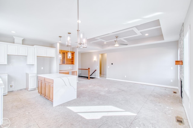 kitchen with a center island, white cabinetry, hanging light fixtures, ceiling fan with notable chandelier, and light stone counters