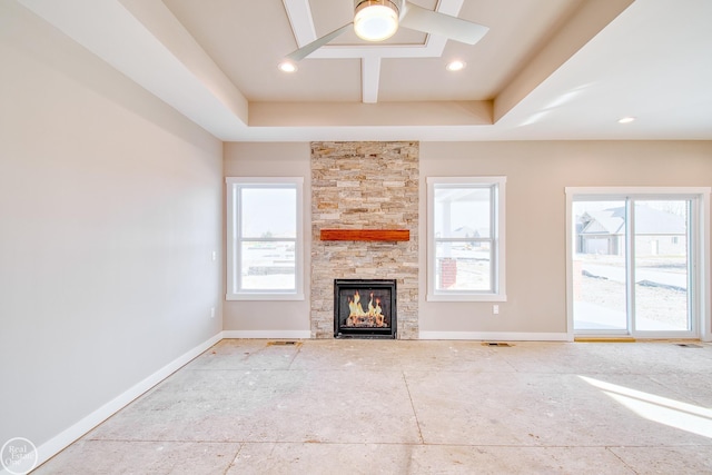 unfurnished living room featuring a stone fireplace, ceiling fan, and a raised ceiling