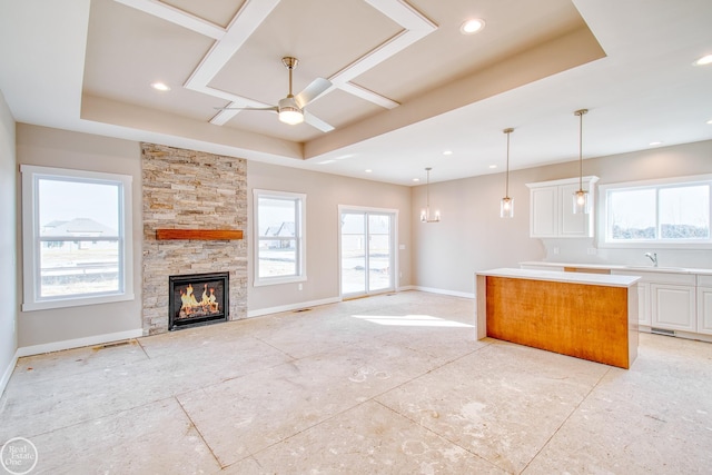 kitchen featuring hanging light fixtures, a tray ceiling, ceiling fan, white cabinetry, and a center island