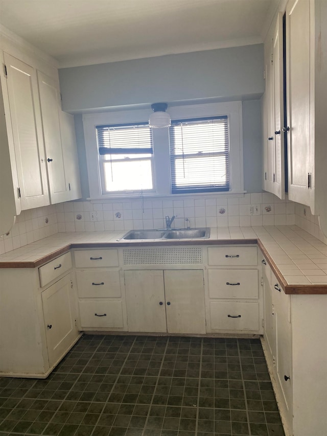 kitchen with sink, white cabinetry, tile counters, and backsplash