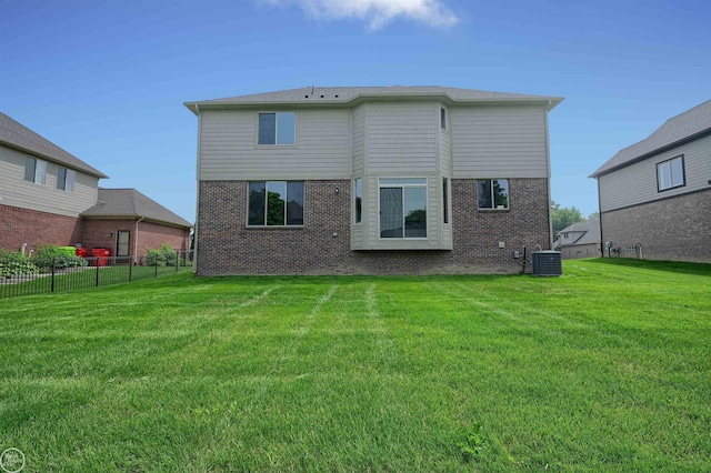 rear view of house with central air condition unit and a yard