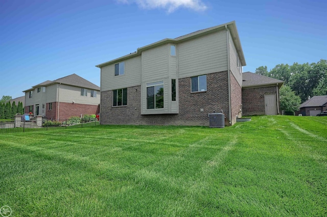 rear view of house featuring central air condition unit and a lawn