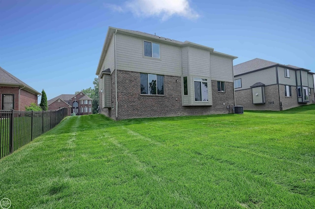 rear view of property featuring central air condition unit and a lawn