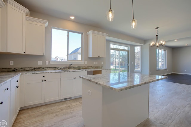 kitchen featuring white cabinets, a wealth of natural light, light stone counters, and a kitchen island