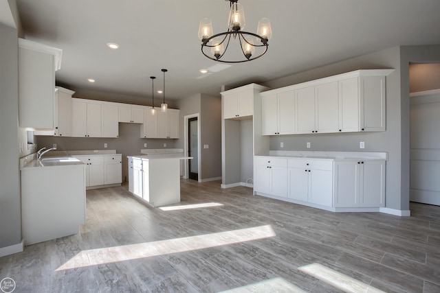 kitchen featuring hanging light fixtures, a kitchen island, white cabinetry, and an inviting chandelier