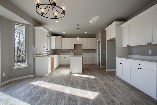 kitchen featuring light hardwood / wood-style flooring, a kitchen island, hanging light fixtures, and a wealth of natural light