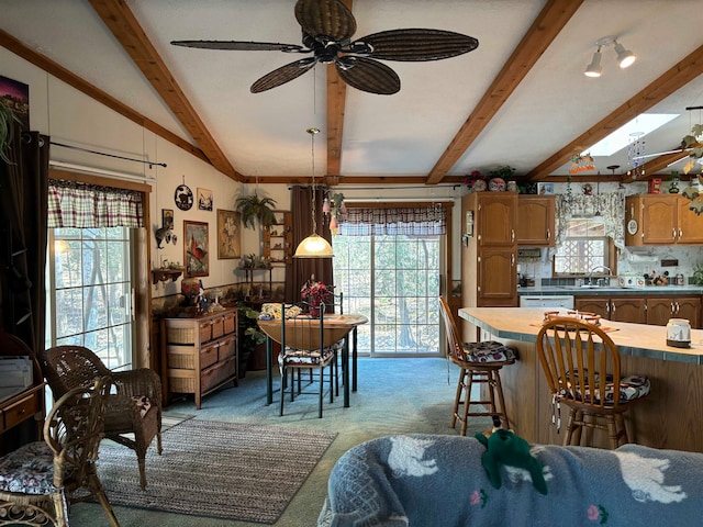 carpeted dining area featuring sink, lofted ceiling with skylight, and ceiling fan