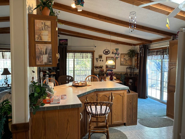 kitchen featuring vaulted ceiling with beams, light colored carpet, a textured ceiling, and kitchen peninsula