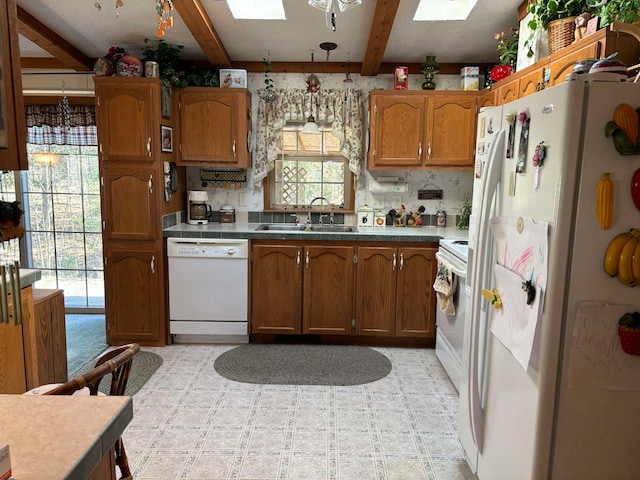 kitchen featuring beamed ceiling, sink, white appliances, and a skylight