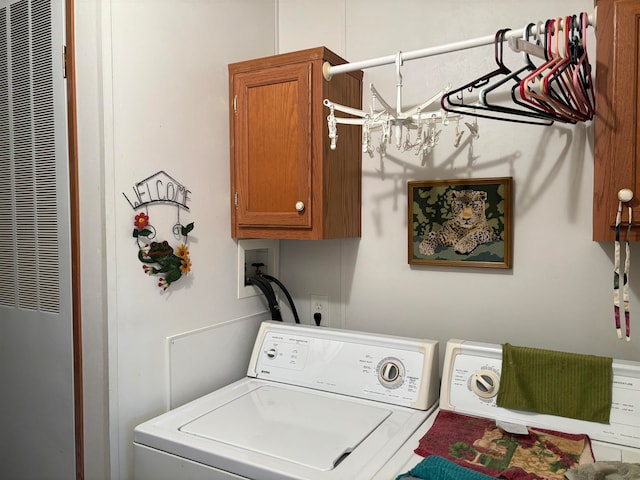 clothes washing area with washer and dryer and cabinets