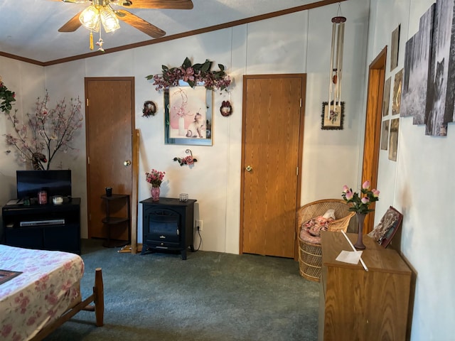 bedroom featuring ceiling fan, ornamental molding, carpet floors, and a wood stove