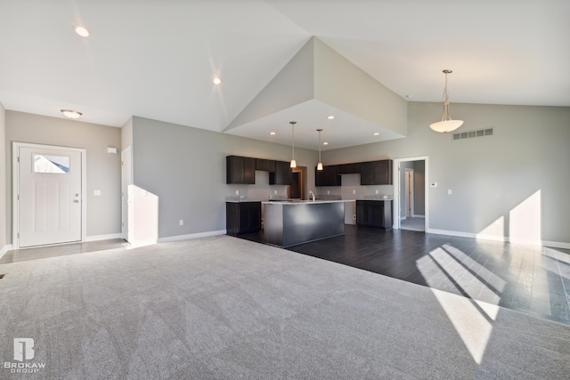 unfurnished living room featuring sink, dark colored carpet, and high vaulted ceiling