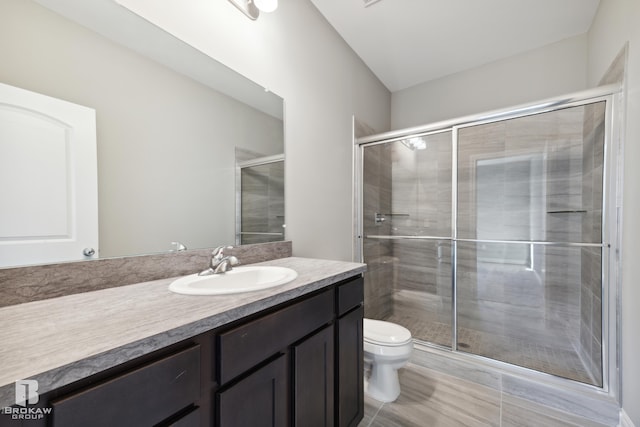 bathroom featuring tile floors, toilet, vanity, and a shower with shower door