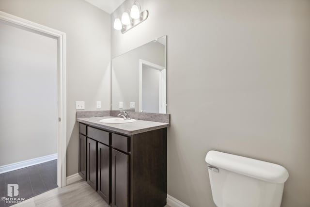 bathroom featuring toilet, large vanity, and hardwood / wood-style flooring