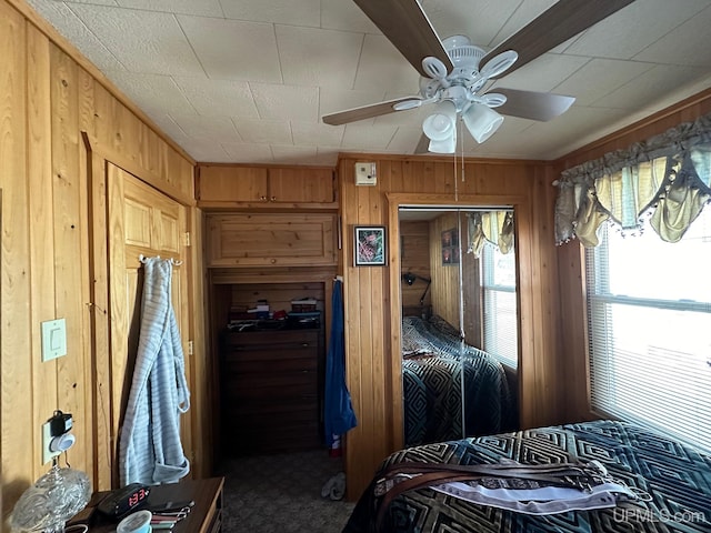 bedroom with a closet, ceiling fan, wood walls, and carpet