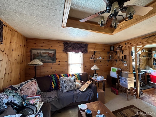 carpeted living room with wood walls and ceiling fan