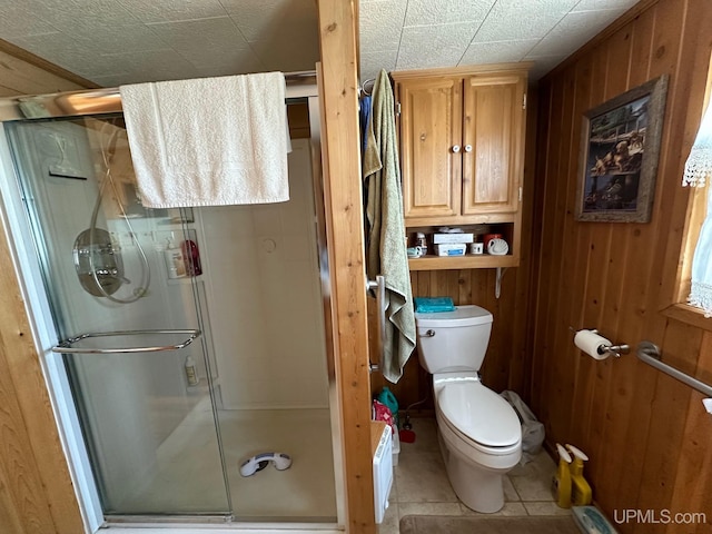 bathroom with walk in shower, wood walls, toilet, and tile floors